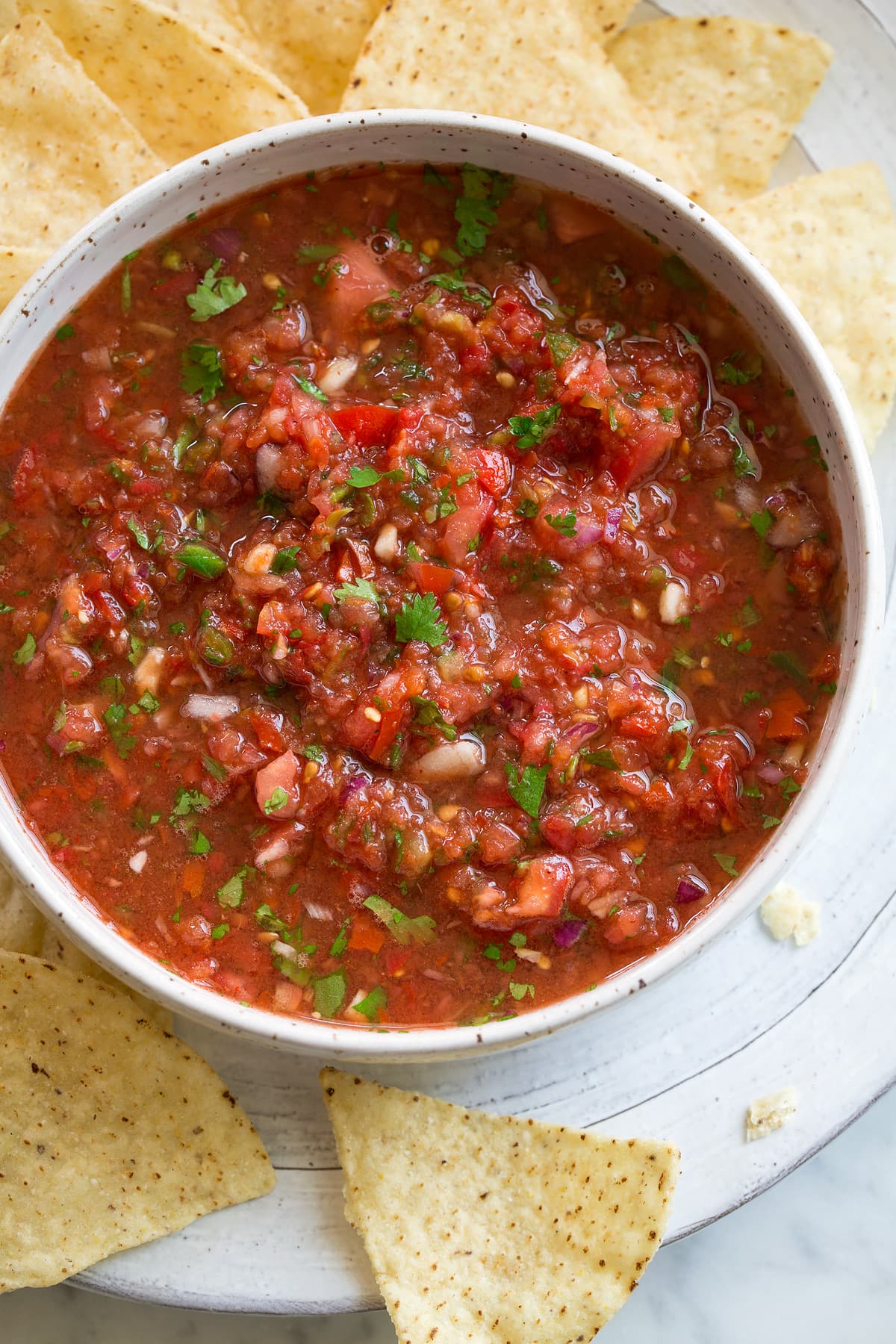 Fresh Homemade Salsa in a white bowl with tortilla chips on the side.