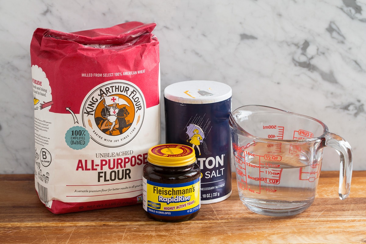 Four ingredients used to make no knead bread shown here including all-purpose flour, yeast, salt and water.