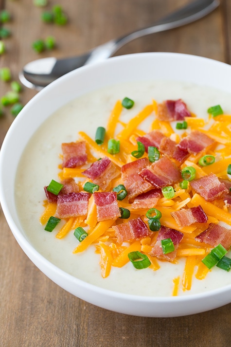 Slow Cooker Loaded Potato Soup in a white bowl topped with bacon, cheese and green onions 