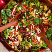 Overhead photo of apple salad in a wooden serving bowl with wooden serving spoons.