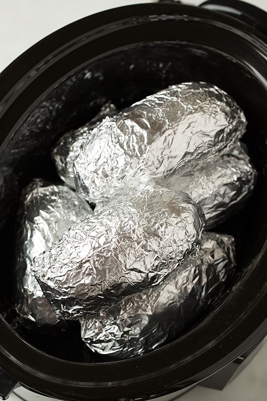 Potatoes wrapped in foil in slow cooker.