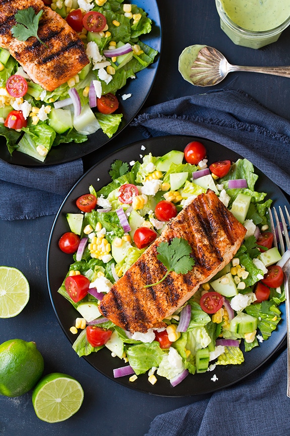 two plates of mexican grilled salmon salad drizzled with avocado ranch dressing