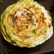 Photo: A roasted cabbage slice is shown from close up. It is golden brown and garnished with parsley.