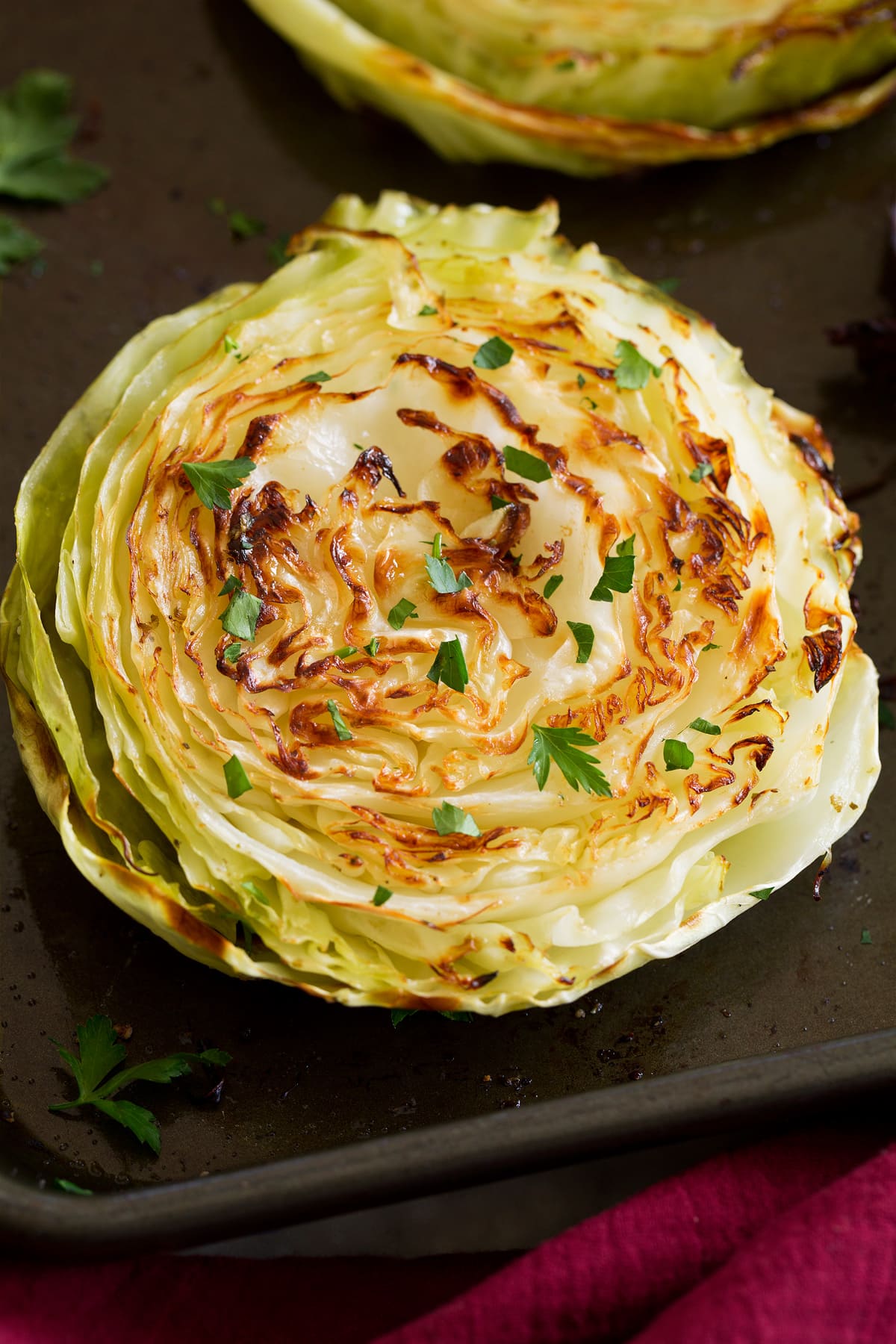 Photo: A roasted cabbage slice is shown from close up. It is golden brown and garnished with parsley.