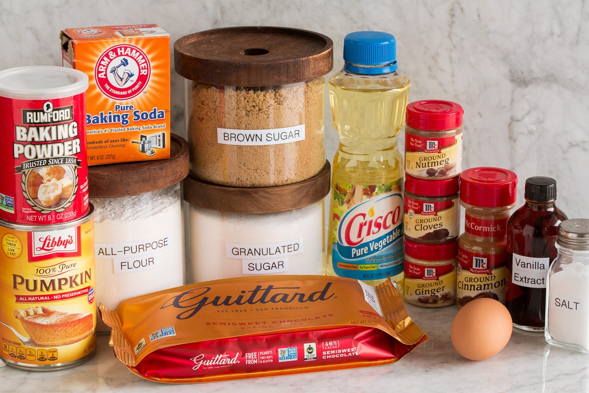 Image of ingredients used to make pumpkin chocolate chip cookies. Includes flour, white sugar, brown sugar, egg, spices, vanilla, chocolate chips, vanilla, baking powder, baking soda and pumpkin.