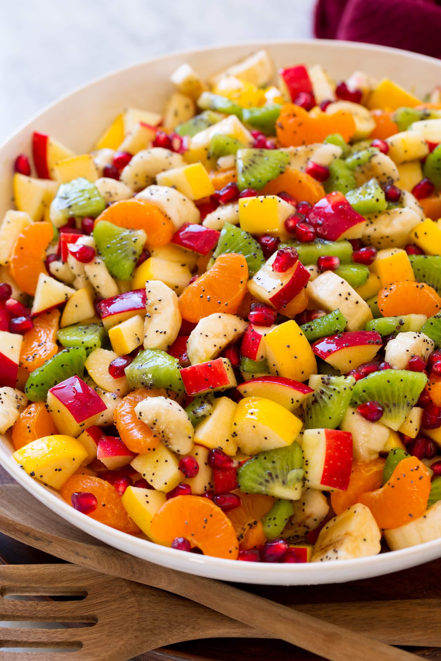 Close up of completed winter fruit salad showing apples, kiwis, oranges, pomegranate, and bananas.