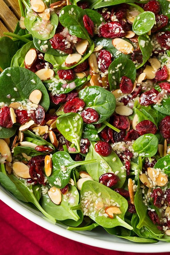 Close up image of spinach salad in a white salad bowl.