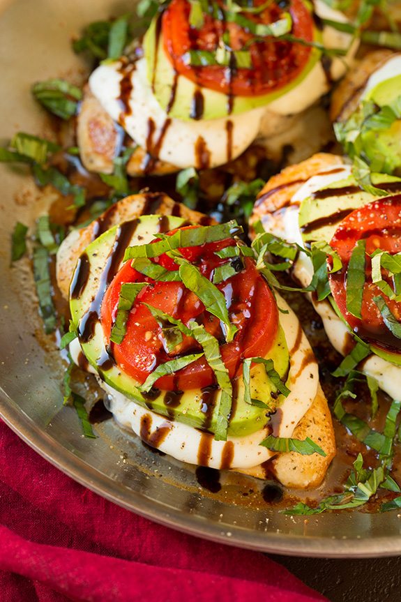 Shown here chicken breasts in a skillet are top with fresh mozzarella avocado tomato basil and balsamic glaze