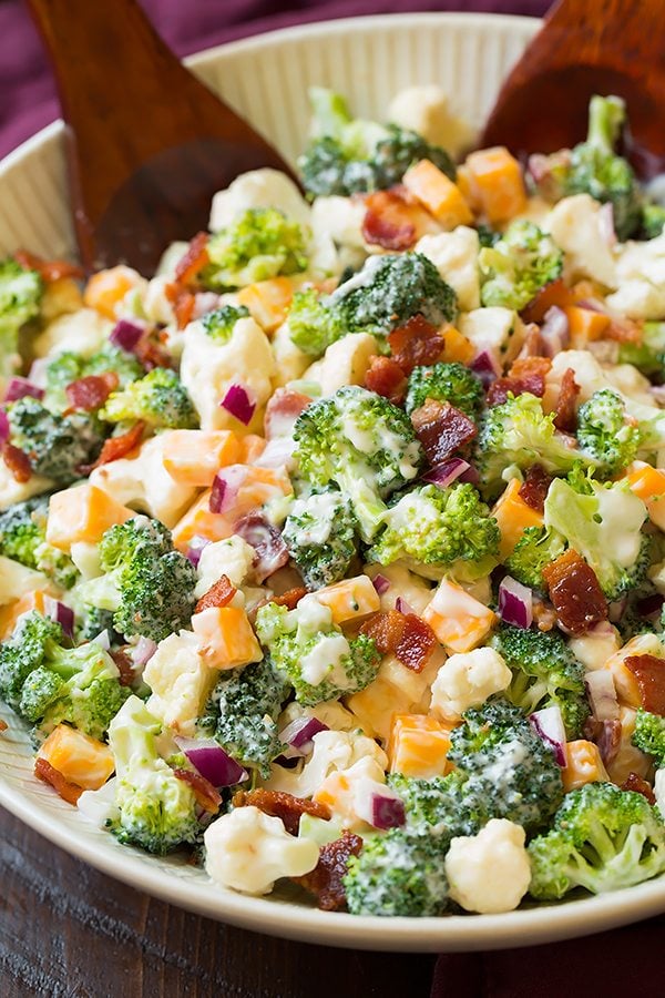 Broccoli and Cauliflower Salad in a bowl with salad servers at the side