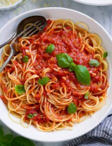 Marinara sauce tossed with spaghetti in a pasta bowl.