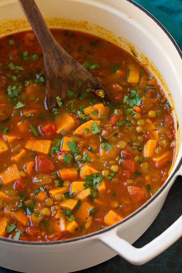 Sweet potato soup in a large white pot with lentils, tomatoes, carrots, onions, and spiced vegetable broth.