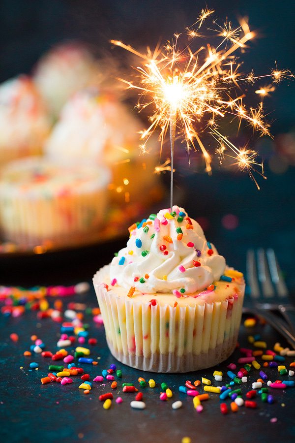 Mini cheesecake with sparkler lit resting in it.