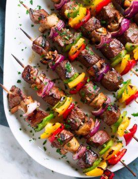 Grilled Steak Kebabs on an oval white platter.