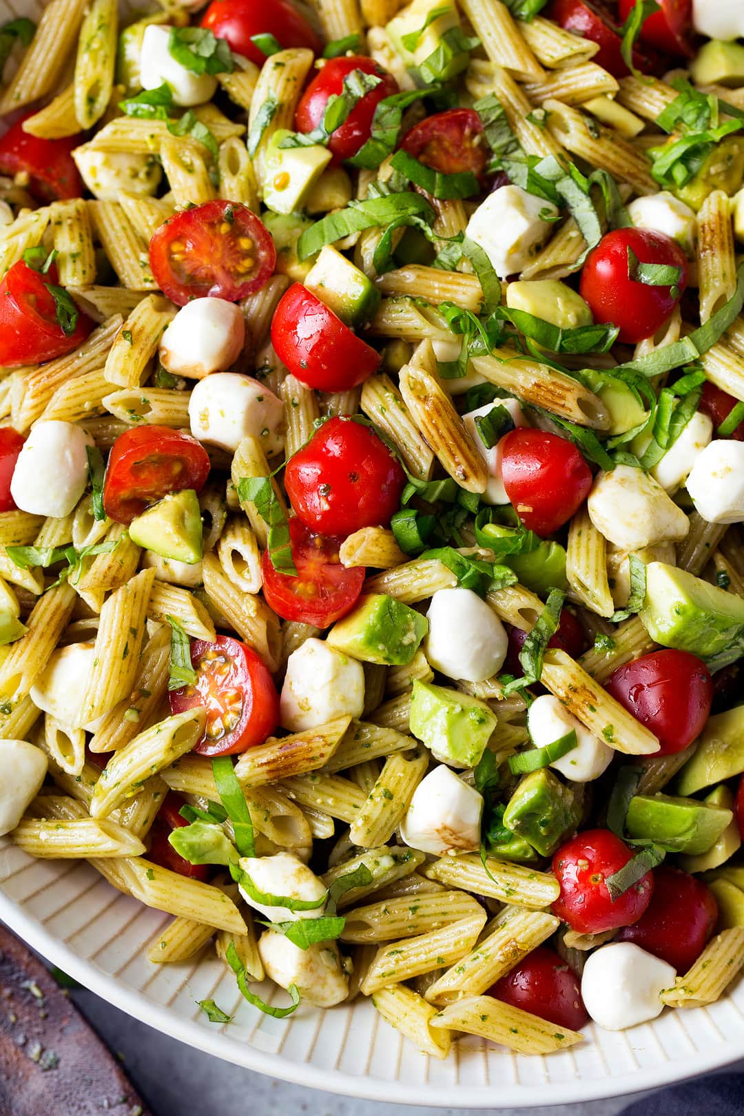 close up of Avocado Caprese Pasta Salad in white bowl