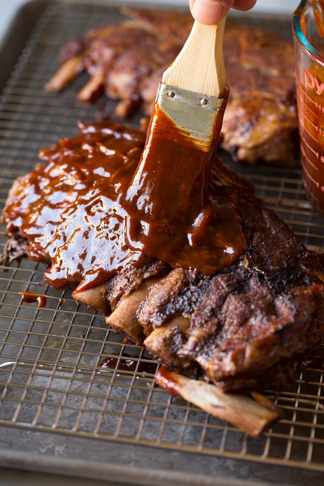 brushing homemade bbq sauce onto Slow Cooker Ribs