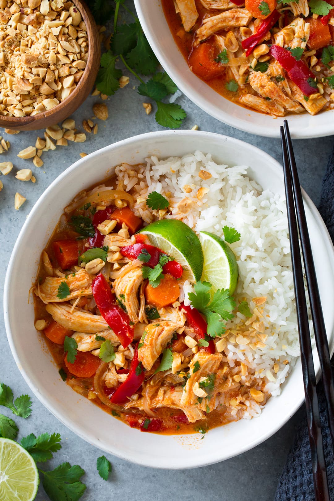 An overhead shot of Slow Cooker Thai Chicken Curry in a white bowl topped with lime wedges