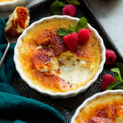 Creme brulee shown on a vintage baking sheet. Sugar shell is broken to show interior custard cream filling.