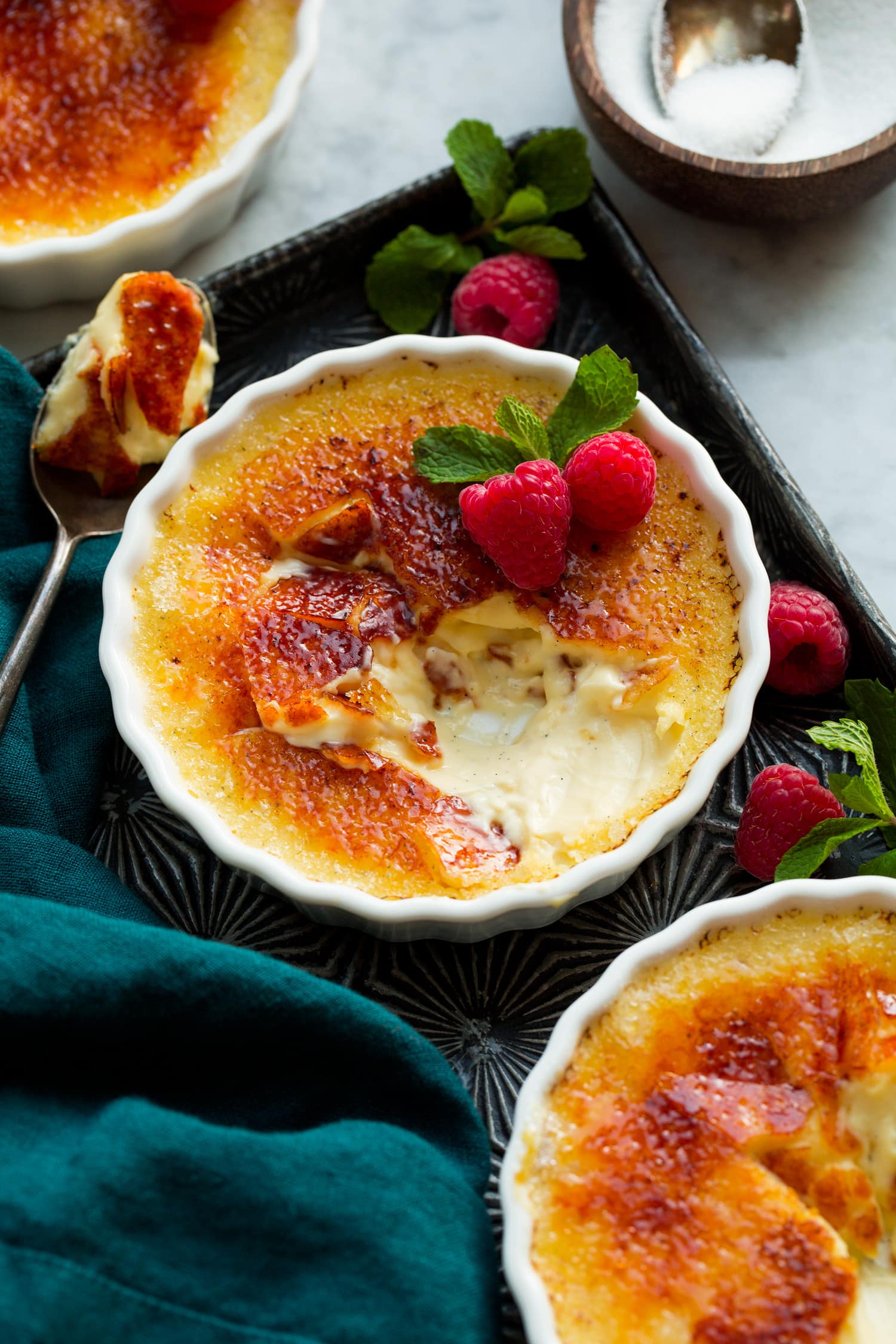 Creme brulee shown on a vintage baking sheet. Sugar shell is broken to show interior custard cream filling.