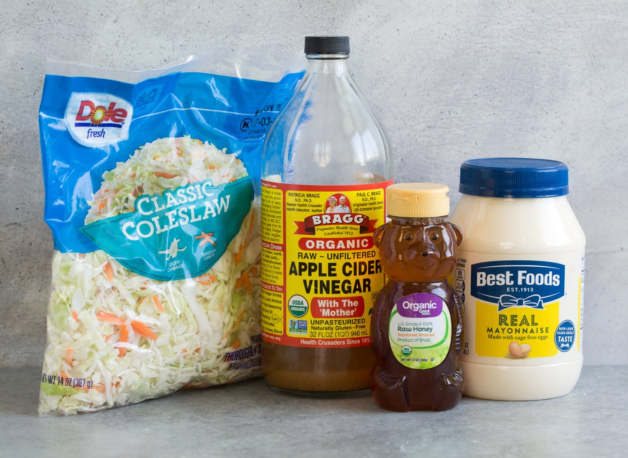 Coleslaw ingredients show here including mayonnaise, honey, apple cider vinegar, and cabbage coleslaw mix.