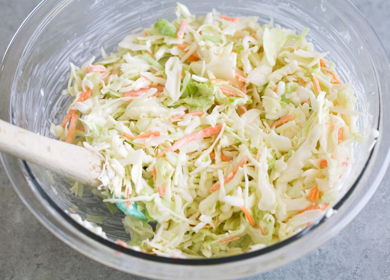 Tossing coleslaw mixture and dressing in mixing bowl