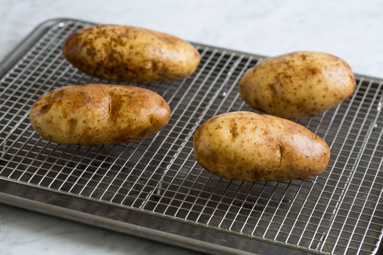 Baked Potatoes shown here set on a wire rack over a baking sheet before baking