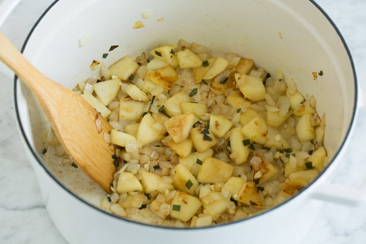 Shown here sauteing apples onions and garlic in large pot for butternut squash soup