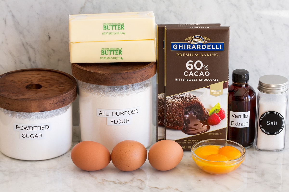 Photo of ingredients needed for chocolate lava cake. Includes chocolate bars, egg yolks, eggs, salt, butter, flour and powdered sugar.