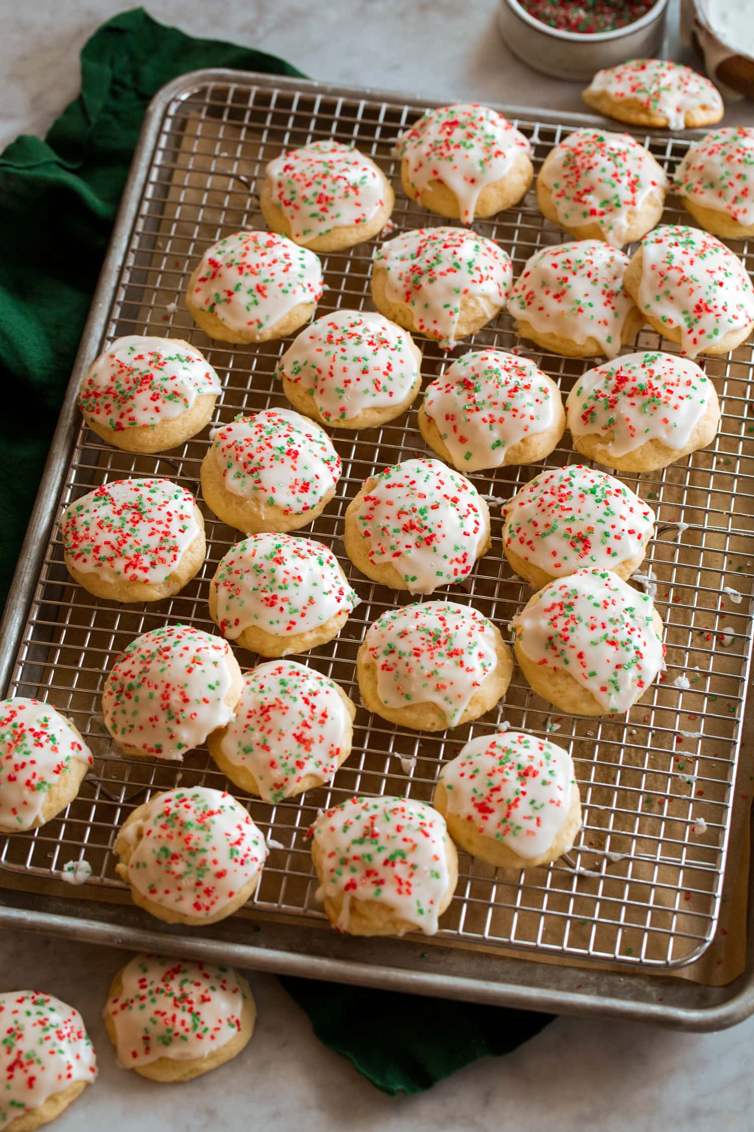 Ricotta cookies with glaze on a wire cooling rack over a baking sheet.