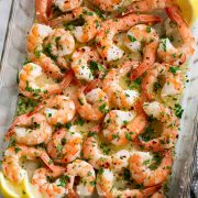 Overhead image of baked shrimp with lemon butter sauce in baking dish.