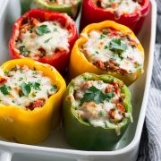 Multi-color stuffed peppers in a white baking dish.