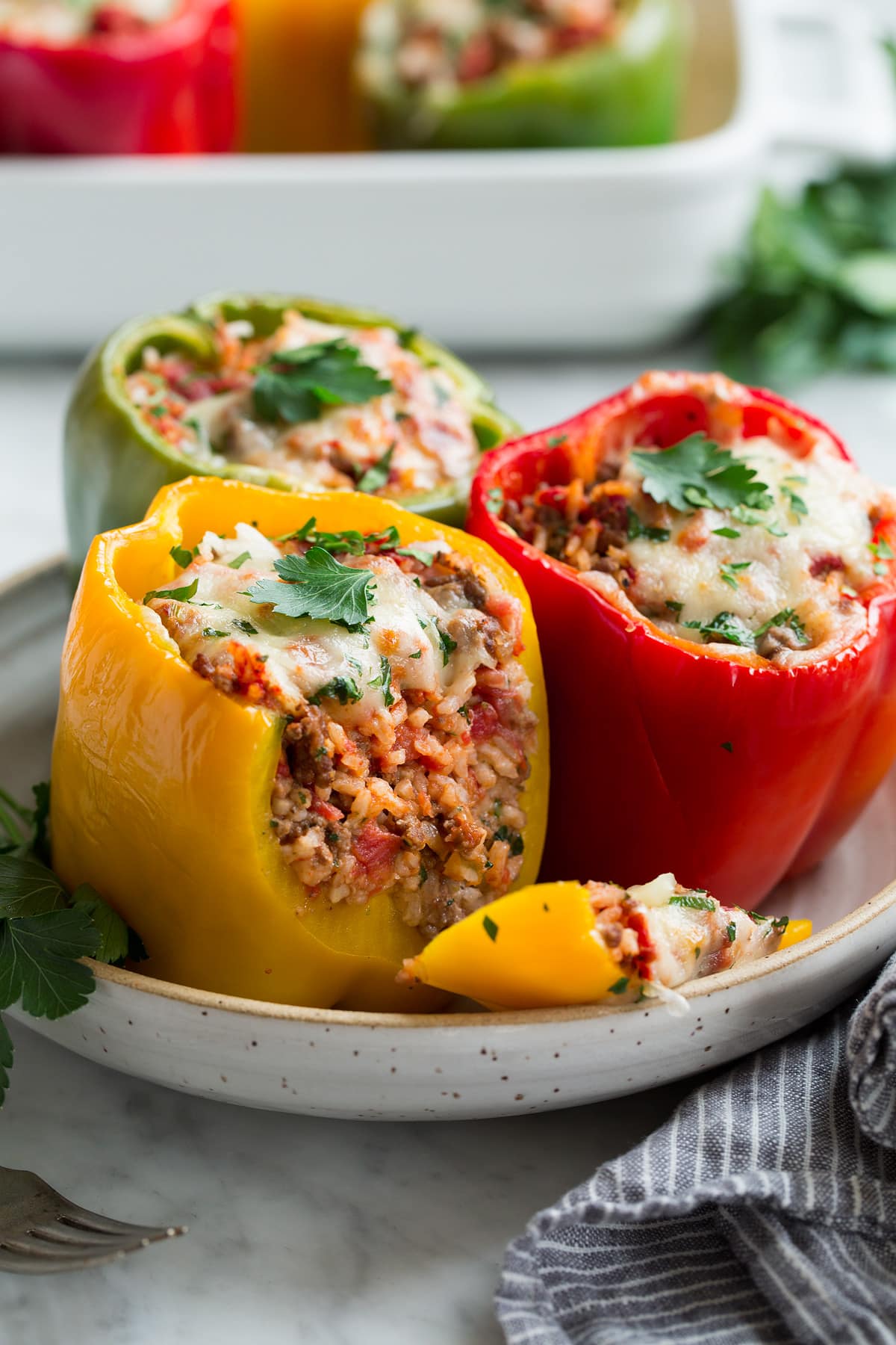 Red yellow and green stuffed pepper in a serving bowl. 