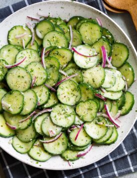 Cucumber Salad in white serving bowl set over a dark grey napkin.