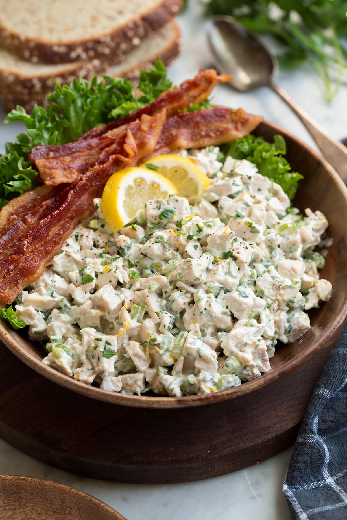 Chicken salad in a wooden serving bowl set over a marble surface.