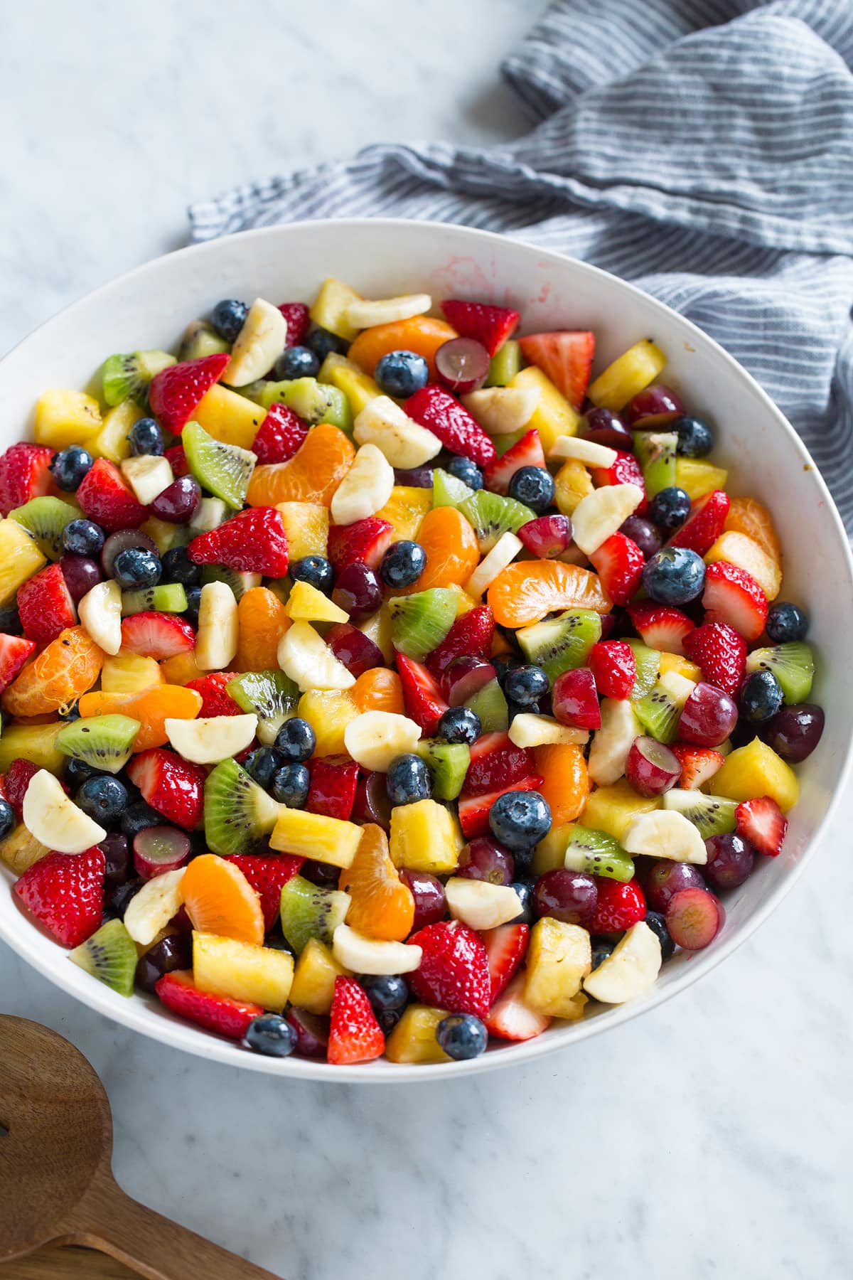 Fruit Salad with chopped fresh fruit in a large salad bowl set over a marble surface.