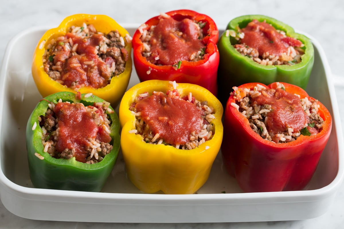 Stuffing par cooked bell peppers in baking dish with rice and ground beef filling. 