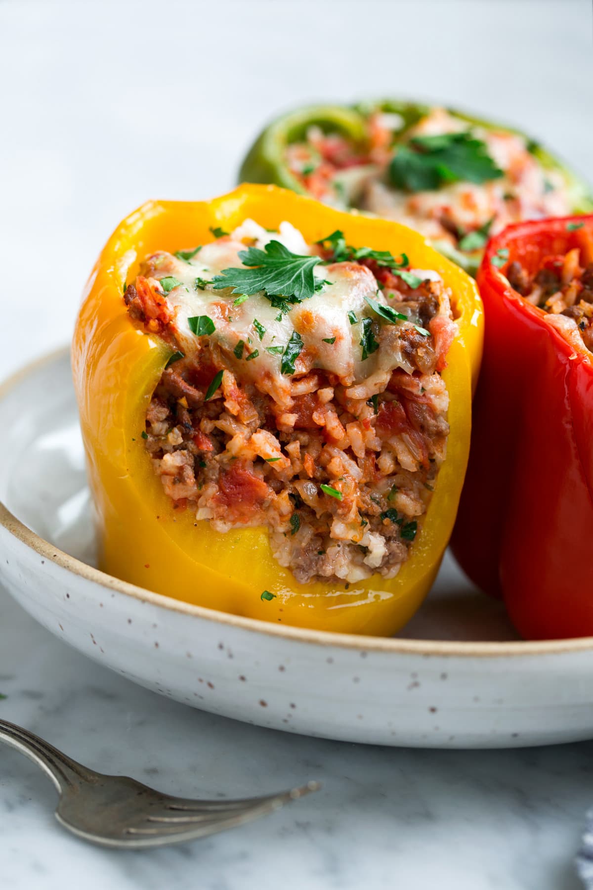 Stuffed Bell Peppers cut in half to show filling including ground beef, rice, tomato sauce and cheese.