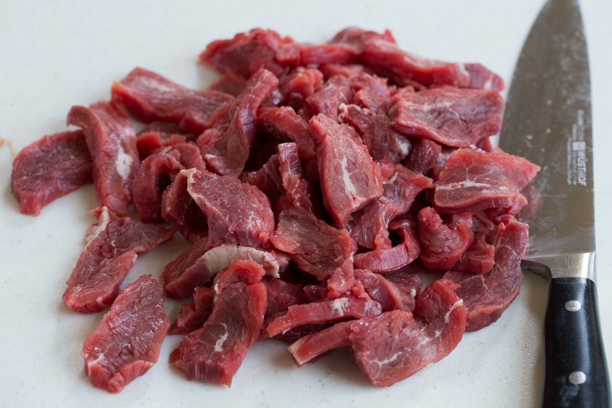 Thinly sliced flank steak on a cutting board.