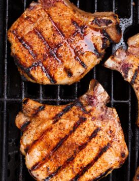 Overhead close up image of two pork chops on a grill.