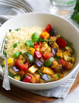 Ratatouille in a wide white bowl with a side of couscous.