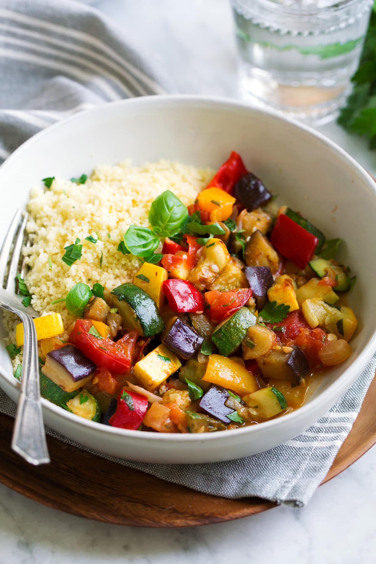 Ratatouille in a wide white bowl with a side of couscous.