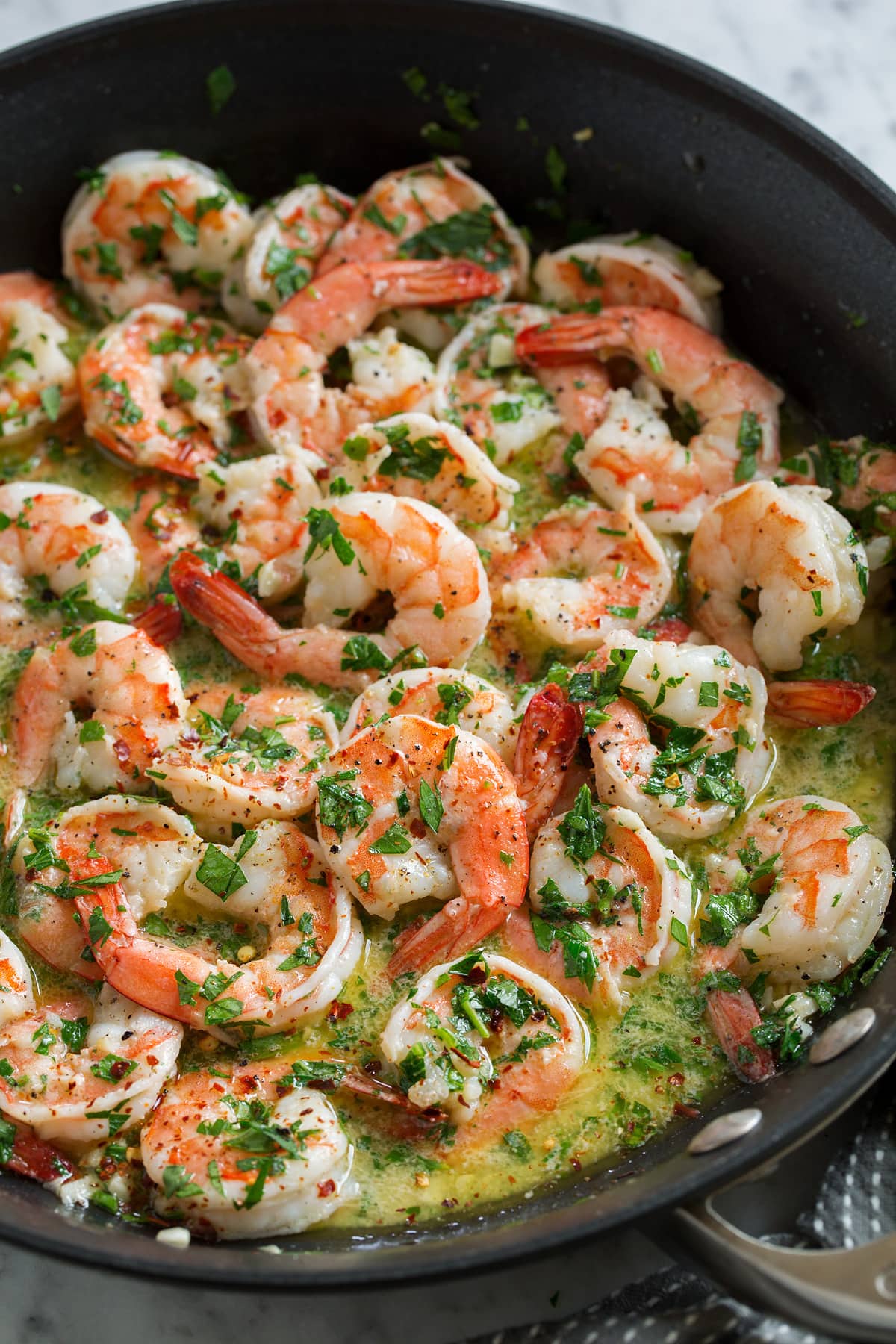 Shrimp scampi in a black skillet with sauce.