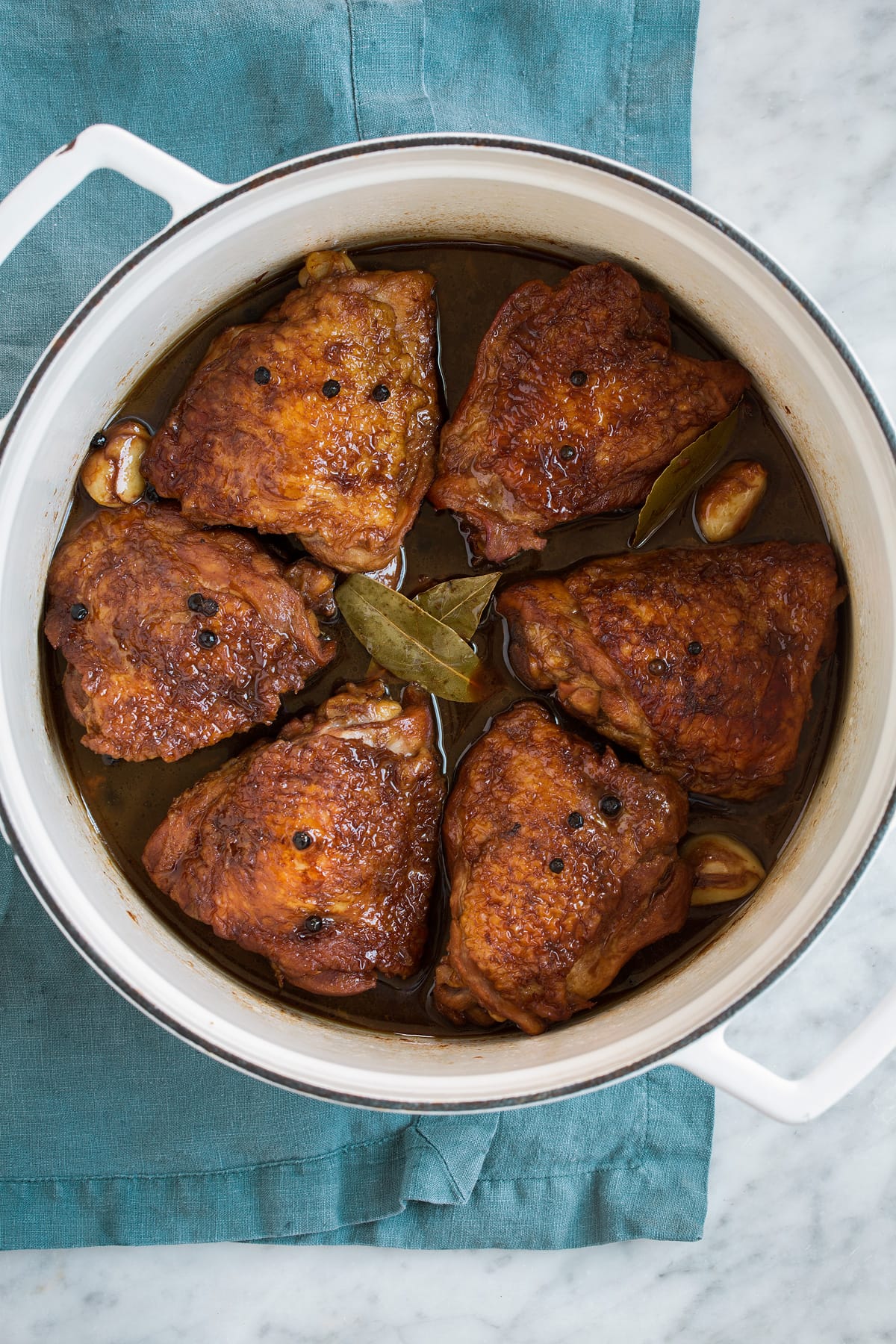 Overhead image of chicken adobo in a white pot.