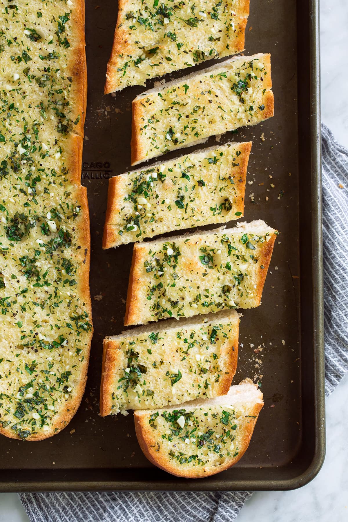 Loaf of garlic bread cut into slices on a baking sheet.