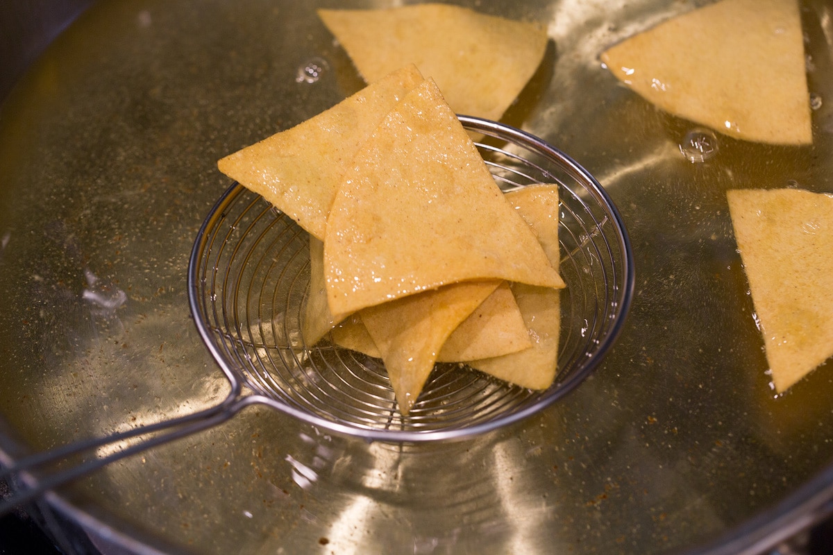 Draining tortilla chips through a wire spider.