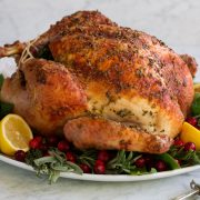 Whole roasted turkey on a serving platter with herbs lemons and cranberries