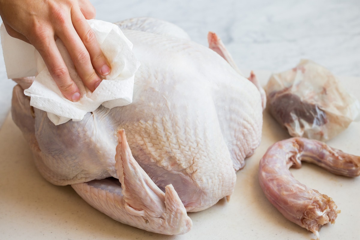 Drying turkey with paper towels so butter adheres better and skin browns better.