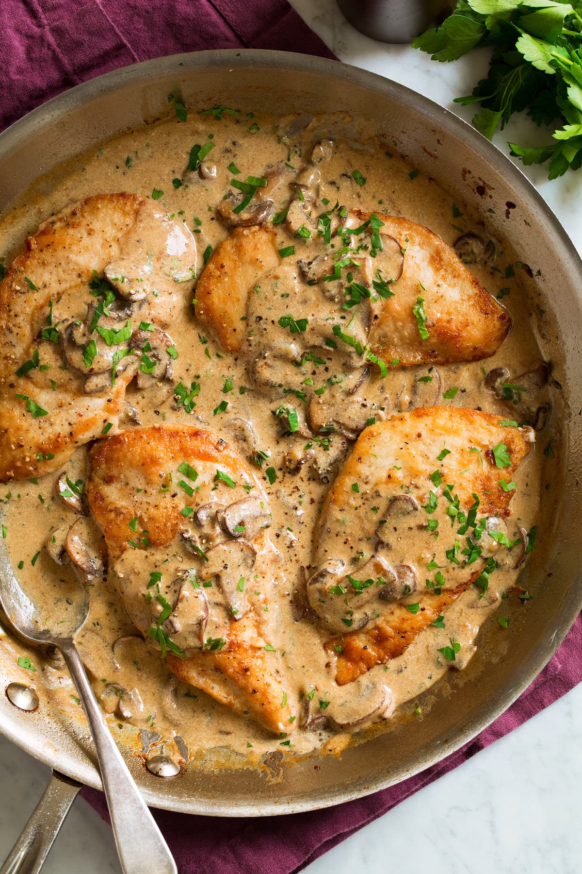 Four servings of chicken marsala in a large skillet covered with creamy chicken marsala wine and mushroom sauce.