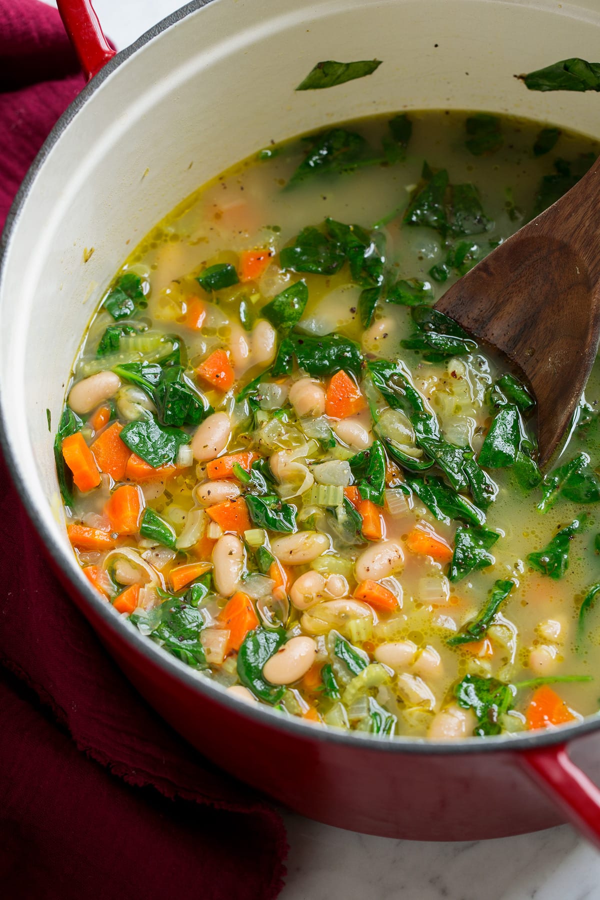 Finished bean soup shown in a large red and white pot.