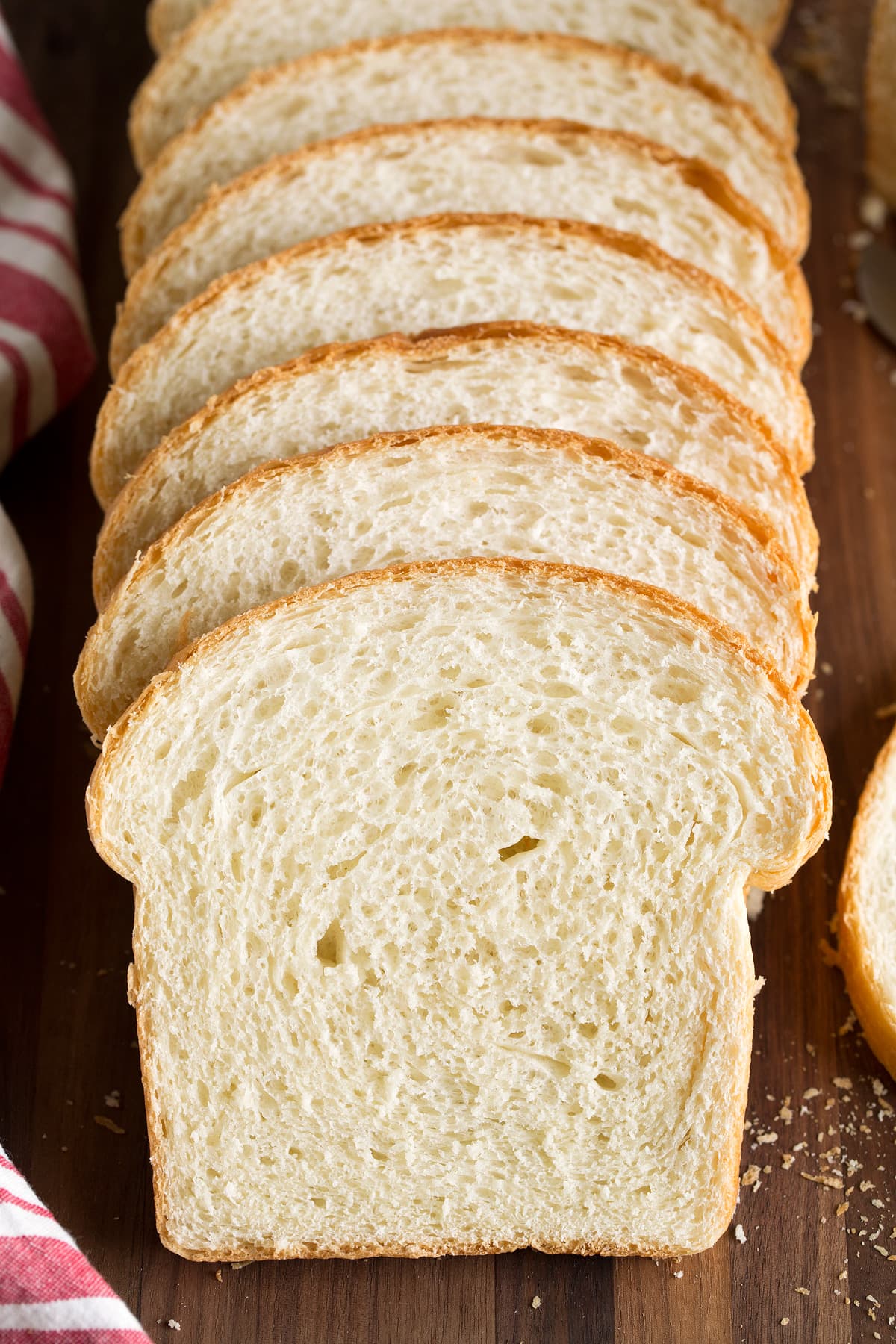 Close up image showing a row of homemade white bread slices on a cutting board.