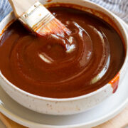 Bowl of bbq sauce with a basting brush resting in the sauce.